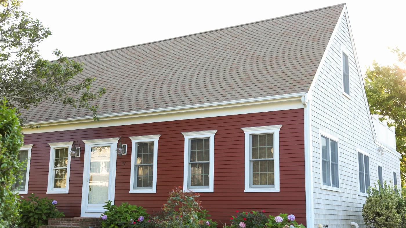 Home with red and white siding with large steep-sloped shingle roof