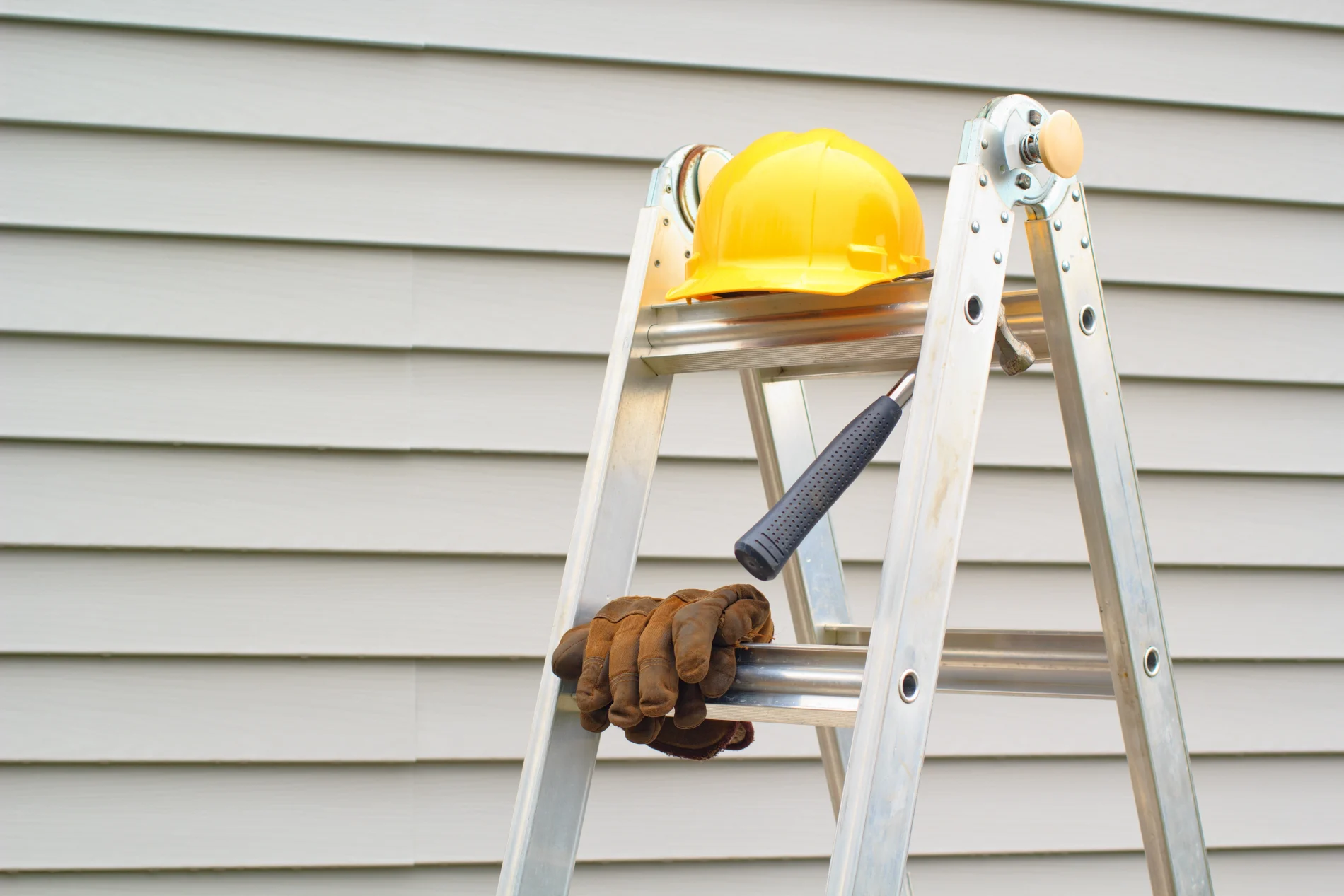 A siding contractor's tools sit on a ladder.