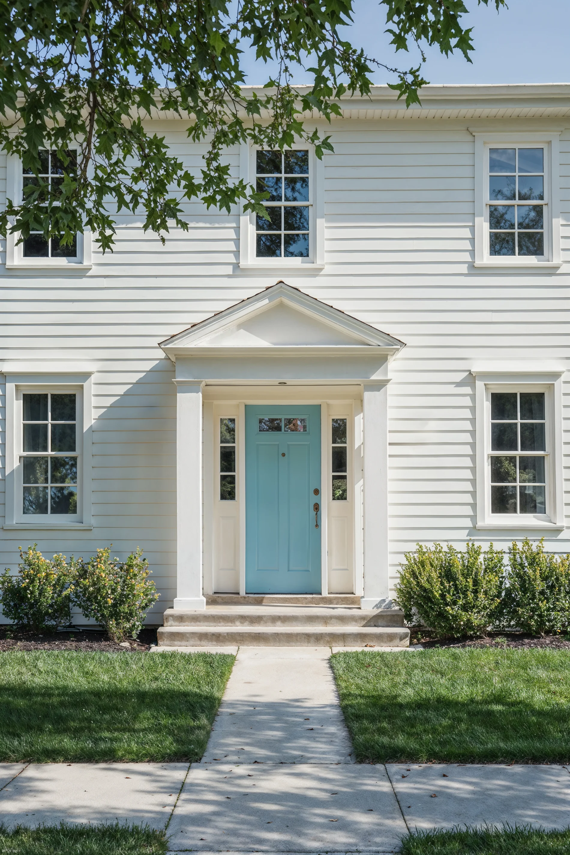 A two-story home with white siding, window frames, and trim. The home’s front door is bright blue.